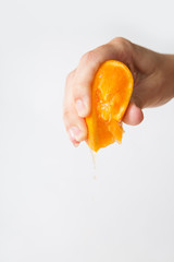 Hand of woman squeezing orange for juice isolated on white background. Cropped shot, closeup. Fresh juice or organic food concept