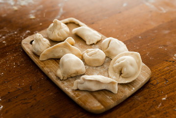 National food,cooking dumplings,dumplings lie on a wooden kitchen table,raw khinkali stacked in a circle on a tray,different choice of food from raw dough,traditional home cooking