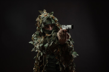 sniper in a camouflage suit poncho with a gun