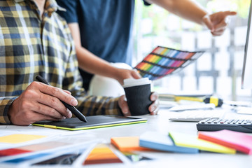 Team of young Interior graphic designer working sketching on graphic tablet and color swatch,...