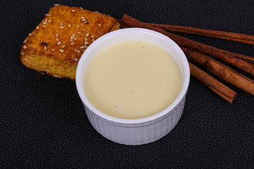 Condenced milk in the bowl with sinnamon and pastry