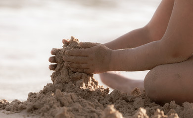 A boy plays in the sand on the beach near the sea.