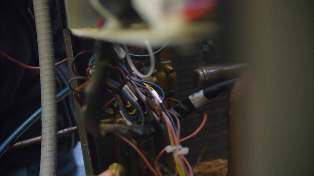 Man working on electrical wiring for air conditioning unit