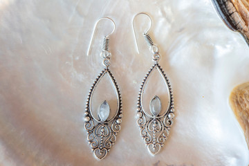 Brass metal pair of beautiful elegant earrings on white natural shell background