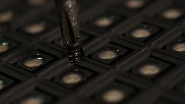 Manually unscrewing screw with hand and screwdriver. Macro.