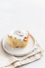 Fragrant freshly baked Cinnamon roll or cinnabon with white cream glaze. Cinnabons recipe. Traditional homemade sweet buns. Pastry, bakery. Side view, close up. Copy space