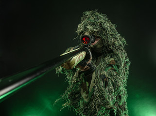 sniper in a poncho camouflage suit and a sniper rifle