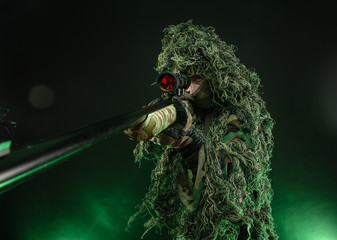 sniper in a poncho camouflage suit and a sniper rifle