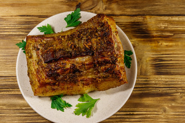 Baked pork belly in a plate on wooden table. Top view