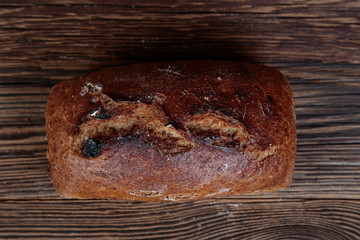 Top view of fresh, crunchy, dark bread with cracked crust. A freshly baked loaf on a wooden, brown, rustic table.