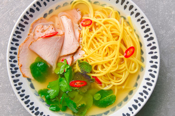 Japanese ramen soup with noodles, beef, egg, fresh parsley and sweet pepper on gray background. Copy space banner.