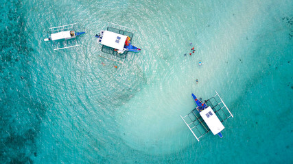 Top view of outrigger boats and swimming tourists in a submerged sandbar near Mactan Island