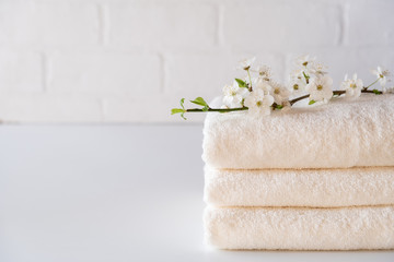 Obraz na płótnie Canvas Stack of three white fluffy bath towels with branch. Spa composition Copy space