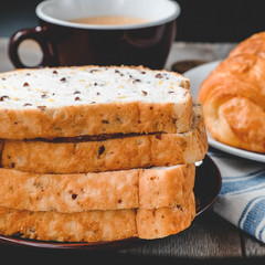 A sliced loaf of sprouted grain and seed bread on white plate closeup
