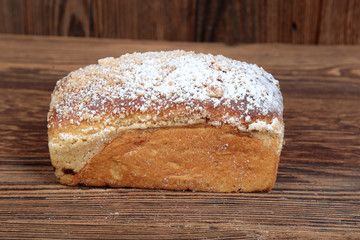 A view, close-up of a homemade, fresh, mold yeast cake stuffed with fruit on a wooden, brown, rustic table.