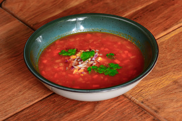 Borscht. Red Ukrainian Russian soup in bowl with sour cream and green onion, isolated on wooden background.