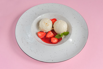 Vanilla strawberry ice cream with strawberry and fruit syrup in a white plate on pastel pink background. Top view.