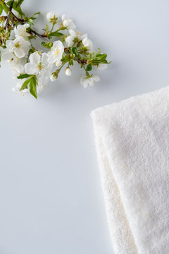 White fluffy bath towels with  branch flowering cherry on white background. Spa and bodycare concept. Spa composition . Copy space