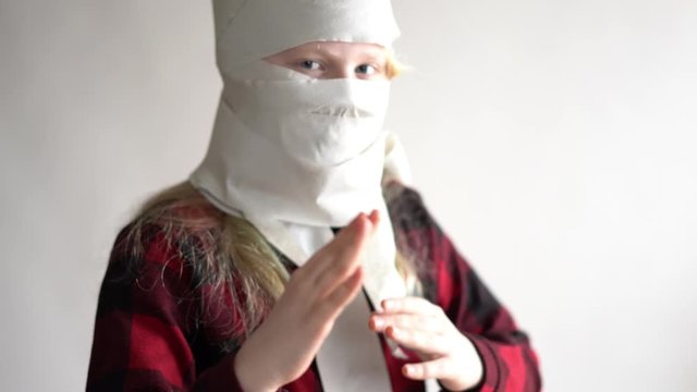 funny video - quarantined due to an epidemic of coronavirus. girl in a mask from toilet paper posing on a gray background.