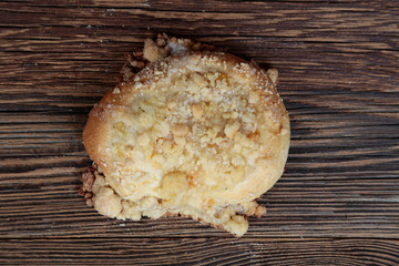 Top view, close-up of fresh homemade  bun with streusel. Cake on a wooden, brown, rustic table.
