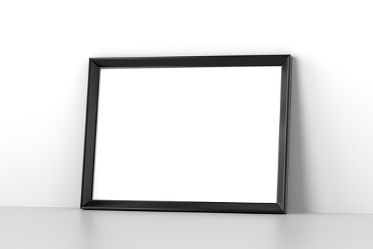 Blank wooden picture frame leaning on white wall