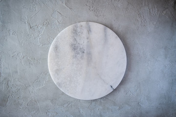 White empty marble texture round board on grey background. Top view. Copy space.