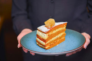Waiter in black uniform, shirt, bringing the ordered dessert and in a cafe or restaurant.