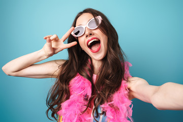 Photo of delighted woman gesturing peace sign while taking selfie photo