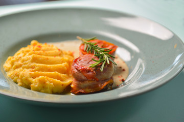 Beef meat pieces with mashed potato, onion gravy and spices. Served on a blue plate over blue mint background.