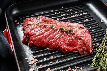 Top blade steak on a grill pan, raw meat, marbled beef . Black background. Top view