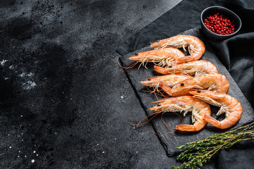 Raw fresh Prawns, shrimps Langostino on a stone Board. Black background. Top view. Copy space
