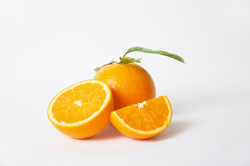 Cut orange parts and whole fruit with green leaves isolated on white background. Closeup shot. Natural vitamin or organic food concept