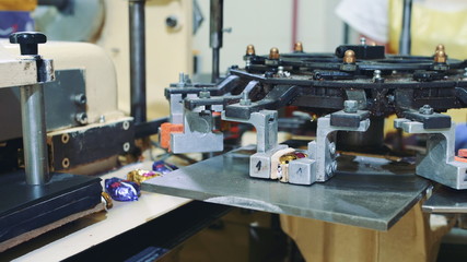 Candy factory. Industrial machine wrapping candies. Modern industrial machine wrapping tasty sweets and putting them on conveyor on confectionery factory.