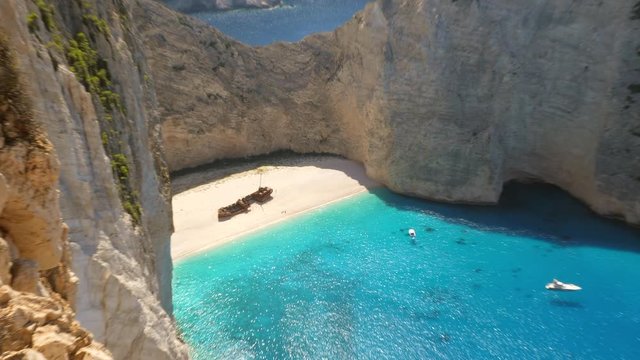 Slow zoom out shot of people taking photos on the empty Navagio Shipwreck Beach on the Island Zakynthos, Greece