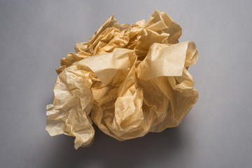 Brown ball of crumped paper on grey background