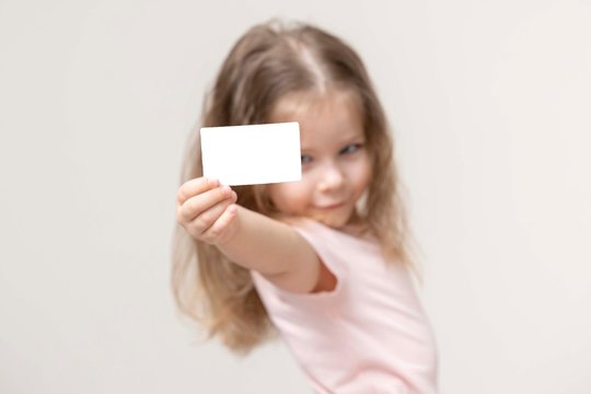 little girl holds a card in front of her and smile, portrait, copy space