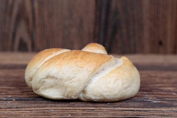 Side view, close-up of a fresh, homemade bread roll with sprinkles on a wooden, brown, rustic table.