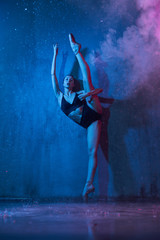 Slim ballerina doing split while standing.