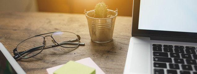 Close up of  businessman's personal objects. Glasses, laptop, tablet, post it and a little plant on...