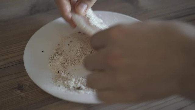 Slow motion of breaded fish fillets fryng in butter in a cast iron skillet.