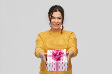 birthday present, surprise and people concept - portrait of happy smiling young woman with pierced nose holding gift box over grey background