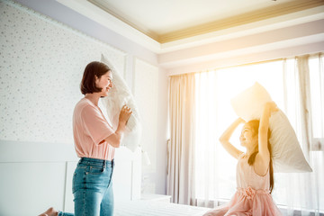  happy mother and daughter playing on the bed in the bedroom