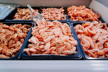 Frozen prawns in a supermarket refrigerated display case. Frozen seafood. Shrimp in the freezer on the window.