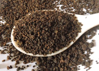 Black tea granules. Tea is an aromatic beverage commonly prepared by pouring hot or boiling water over cured leaves of the Camellia sinensis, an evergreen shrub (bush) native to East Asia.