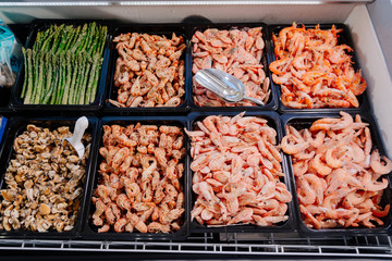 Showcase with seafood and frozen asparagus in a supermarket. Freezer showcase with seafood.