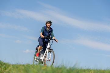 Naklejka premium Querfeldein mit dem E-Bike durch den Frühling, Frau genießt Fahrrad fahren in der Natur.