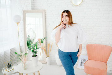 Beautiful plus size female model dressed in blank white shirt posing against the background of a...
