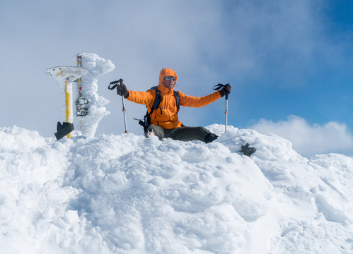  High mountaineer dressed bright orange softshell jacket on the snowy mountain summit.  Active people concept image on Velky Krivan, SLovakian Tatry.