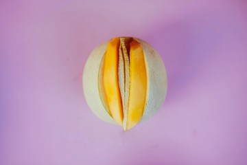 Sliced open melon with yonic fruit assortment over bright colorful background.