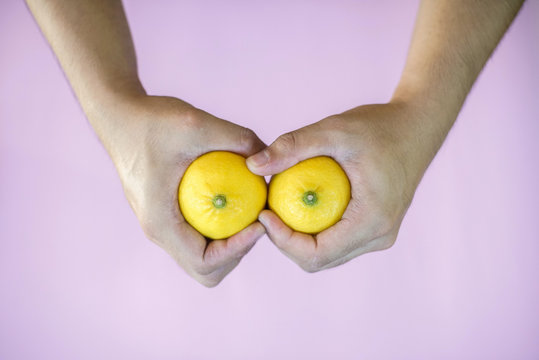 A pair of hands holding lemons with a firm grip.